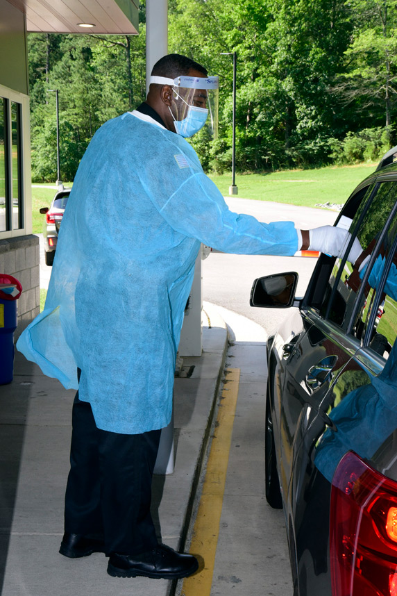 a person takes another's temperature from a car window